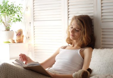 kitap okurken yatakta yatan genç kadın