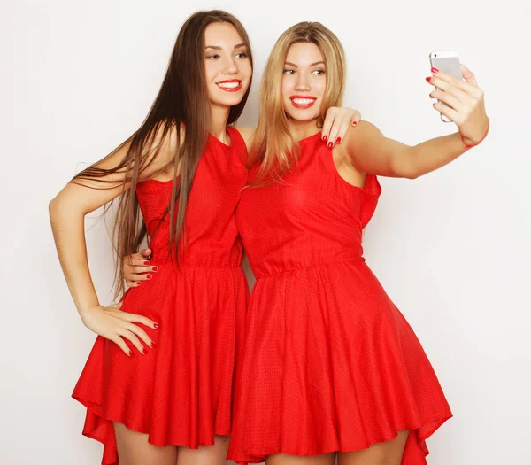 Две женщины в красном платье делают селфи — стоковое фото