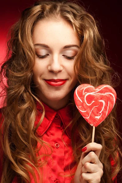 Frau mit Herz Karamell auf rotem Hintergrund — Stockfoto