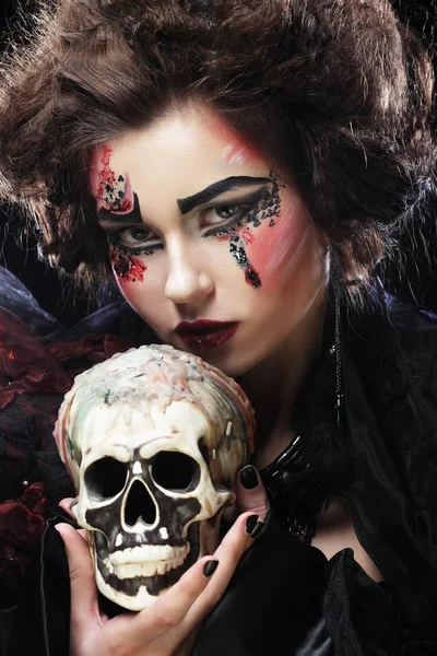 Young beautiful witch holding a skull — Stock Photo, Image