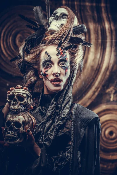Jovem bruxa a esconder o crânio. Maquiagem brilhante e fumar- tema de Halloween . — Fotografia de Stock