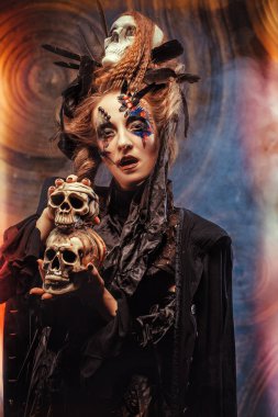 Kafatası kıran genç cadı. Parlak makyaj ve sigara Cadılar Bayramı teması.