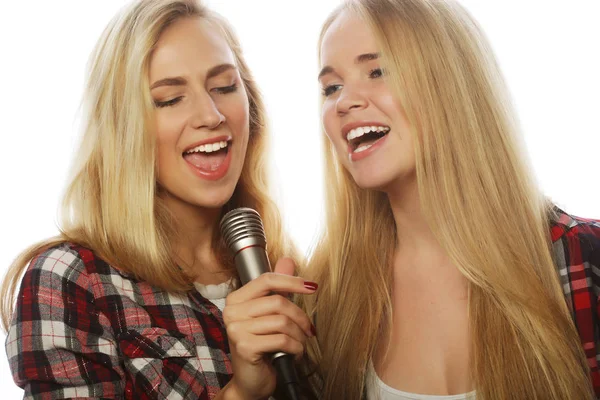 Två skönhetstjejer med en mikrofon som sjunger och har roligt — Stockfoto