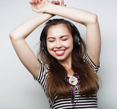 Woman with headphones listening music. Music girl dancing agains clipart