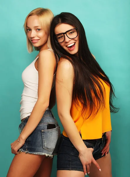 Two young girl friends standing together and having fun. Over bl — Stock Photo, Image