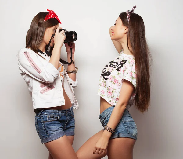 Happy girls friends taking some photos with camera, over white background — Stock fotografie