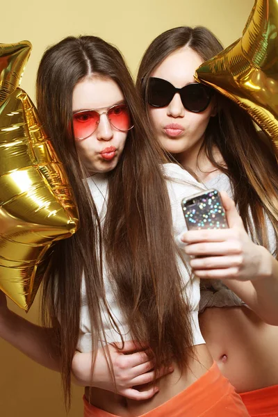 Dos amigas adolescentes con globos de oro hacen selfie en una p —  Fotos de Stock