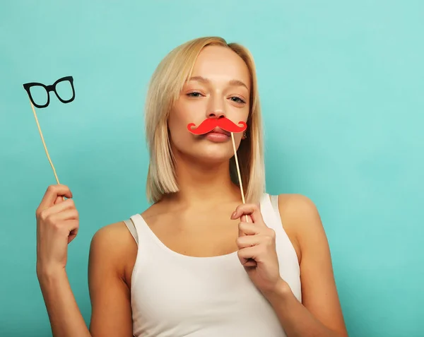 Estilo de vida e conceito de pessoas: Menina feliz vestindo bigodes falsos e óculos sobre fundo amarelo . — Fotografia de Stock