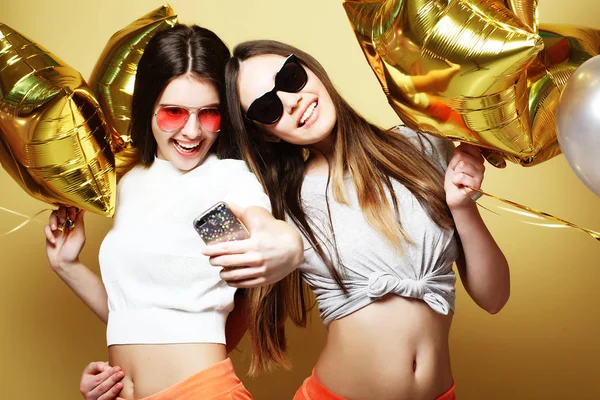 Dos amigas adolescentes con globos de oro hacen selfie en una p —  Fotos de Stock