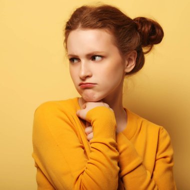 genç kadın sarı arka plan üzerinde düşünme çatık