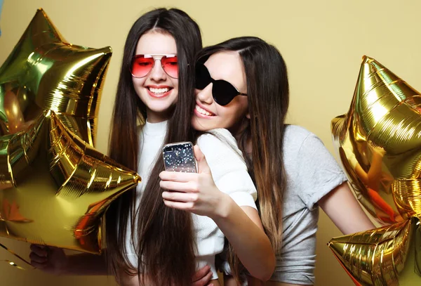 Twee tienermeisjes vrienden met gouden ballonnen maken een selfie op een p — Stockfoto