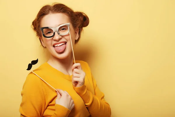 Mujer joven con bigotes falsos y gafas sobre fondo amarillo — Foto de Stock