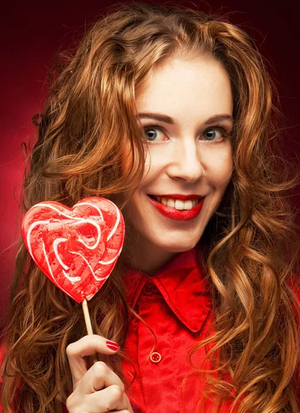 Mujer con corazón caramelo sobre fondo rojo — Foto de Stock