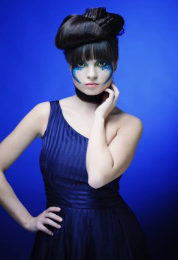 Parlak makyaj mavi arka plan ile genç kadın