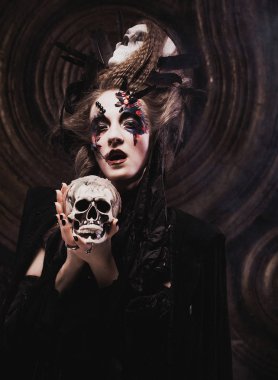 Kafatası kıran genç cadı. Parlak makyaj ve sigara Cadılar Bayramı teması.
