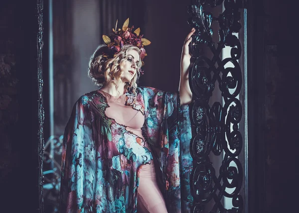 Piękna kobieta w sukience w kwiatowych kolorach stoi w pałacu — Zdjęcie stockowe
