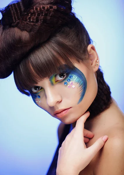 Mujer joven con brillante maquillaje sobre fondo azul — Foto de Stock