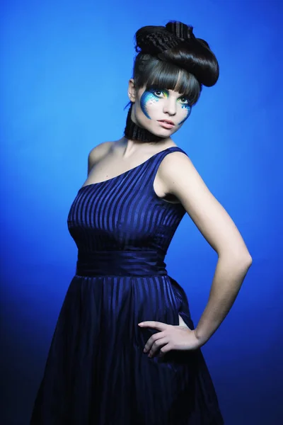 Mujer joven con brillante maquillaje sobre fondo azul — Foto de Stock