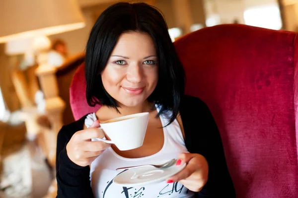 Mladá žena sedí v kavárně a pije kávu — Stock fotografie