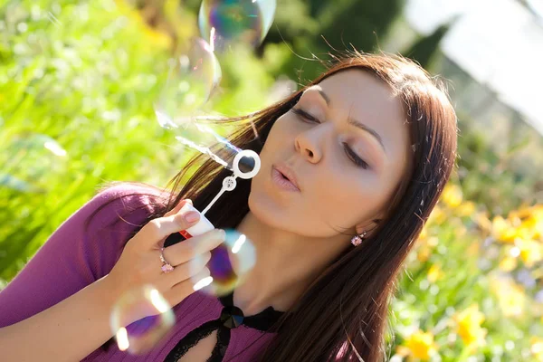 Дівчина дме мильну бульбашку на фоні трави — стокове фото