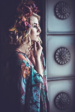 Çiçek rengi bir elbise içinde güzel bir kadın. Çiçek desenli bir çelenk.