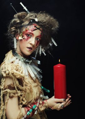 Elinde mum tutan karnaval kostümü giyen genç bir kadın..