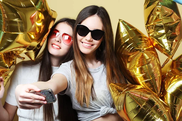 Two teenage girls friends with gold balloons  make selfie on a p — Stock Photo, Image