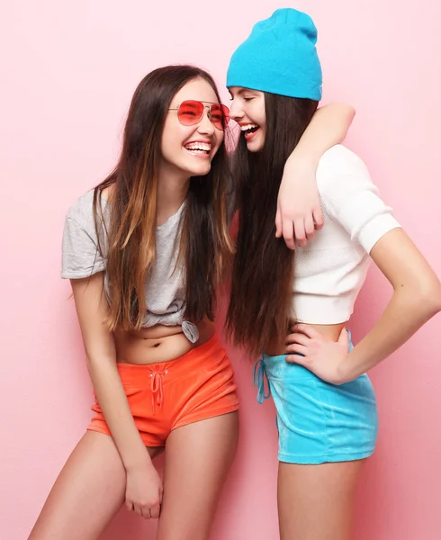 Glücklich lächelnd hübsche Teenager-Mädchen oder Freunde, die sich über rosa umarmen — Stockfoto