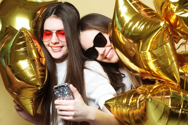 Две подружки-подростки с золотыми шариками делают селфи на р — стоковое фото