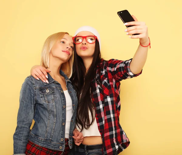 Chicas felices con teléfono inteligente sobre fondo amarillo. Yo feliz. — Foto de Stock
