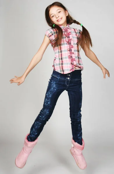 Little girl jumps on a gray  background — Stock Photo, Image
