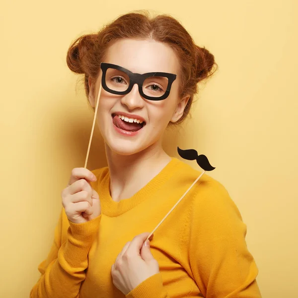 Mujer joven con bigotes falsos y gafas sobre fondo amarillo — Foto de Stock