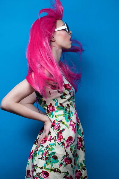 Fashion model with pink hair and big sunglasses over blue  background — Stock Photo, Image