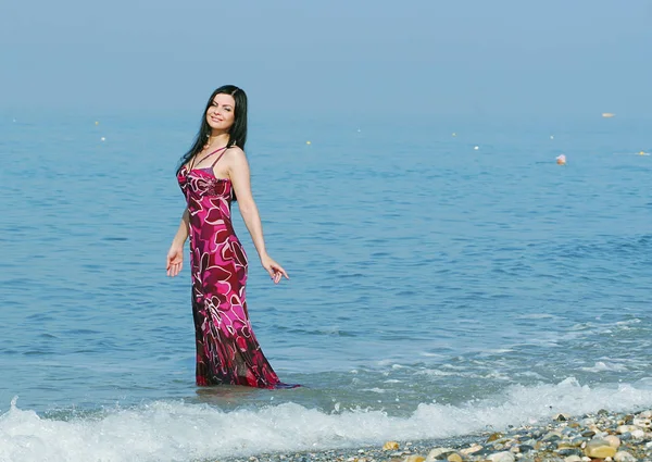 Frau im rosa Kleid am Meeresstrand — Stockfoto