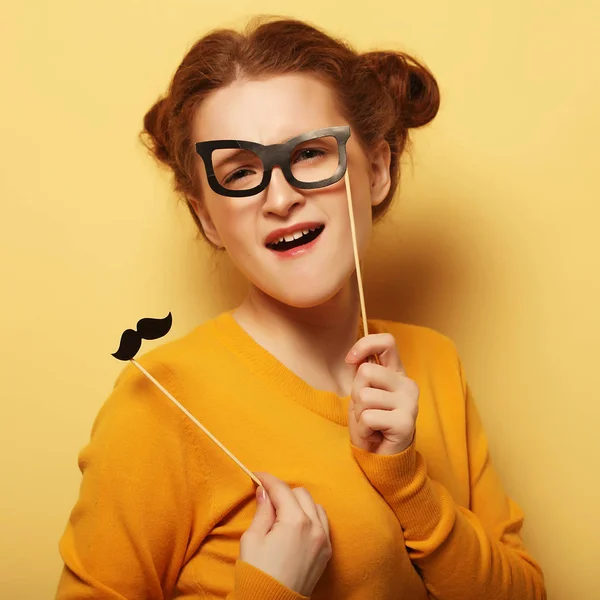 Junge Frau mit falschem Schnurrbart und Brille über gelbem Rücken — Stockfoto