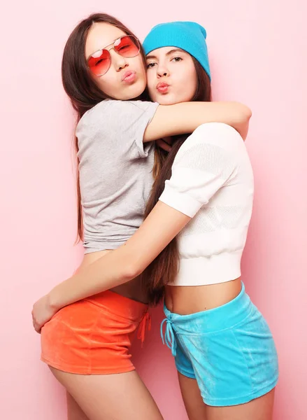 Glücklich lächelnd hübsche Teenager-Mädchen oder Freunde, die sich über rosa umarmen — Stockfoto