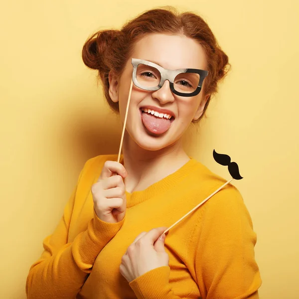 Mujer joven con bigotes falsos y gafas sobre fondo amarillo — Foto de Stock