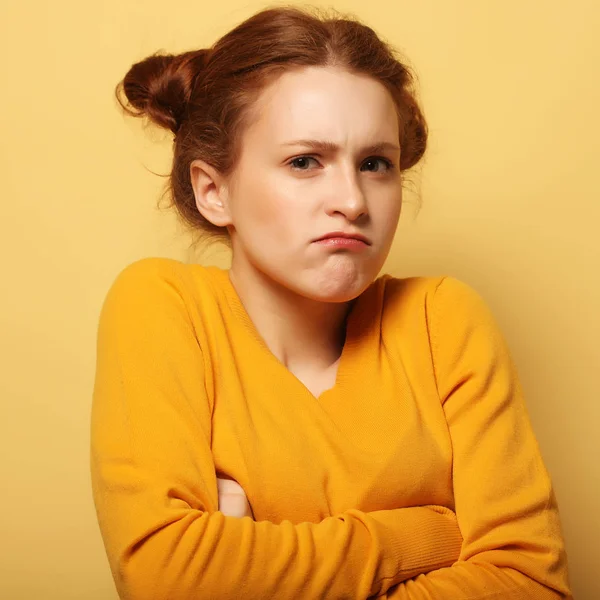 Fronsen jonge vrouw denken op gele achtergrond — Stockfoto