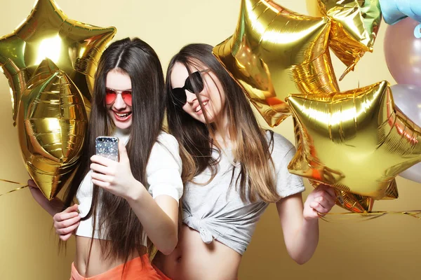 Two teenage girls friends with gold balloons  make selfie on a p — Stock Photo, Image