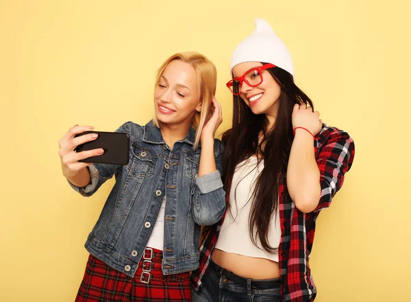 Chicas felices con teléfono inteligente sobre fondo amarillo. Yo feliz. —  Fotos de Stock
