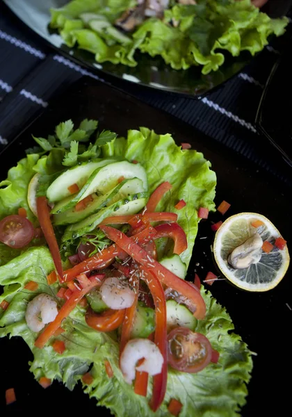 Köstlicher Salat auf schwarzem Teller — Stockfoto