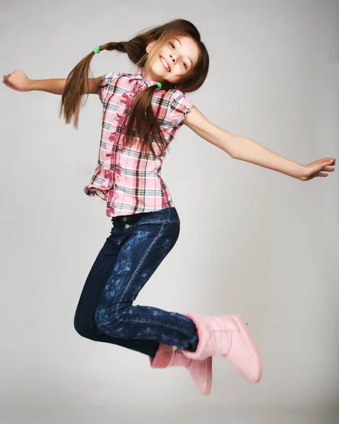 Menina salta em um fundo cinza — Fotografia de Stock