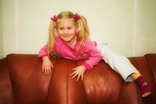 Szőke kislány hátoldalán a kanapén — Stock Fotó