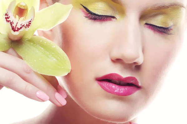 Ung kvinna med ljusa make up håller orkidé — Stockfoto
