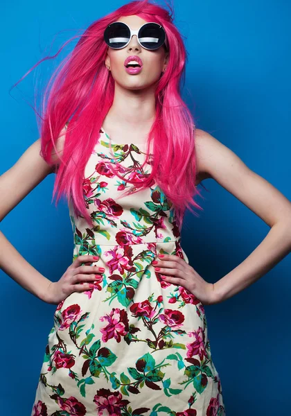 Fashion model with pink hair and big sunglasses over blue  background — Stock Photo, Image