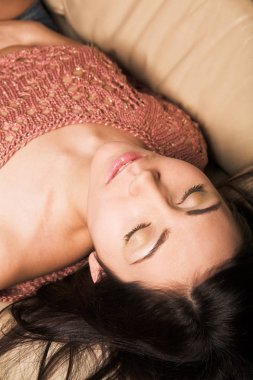 Güzel bir kadın beyaz bir kanepede dinleniyor.