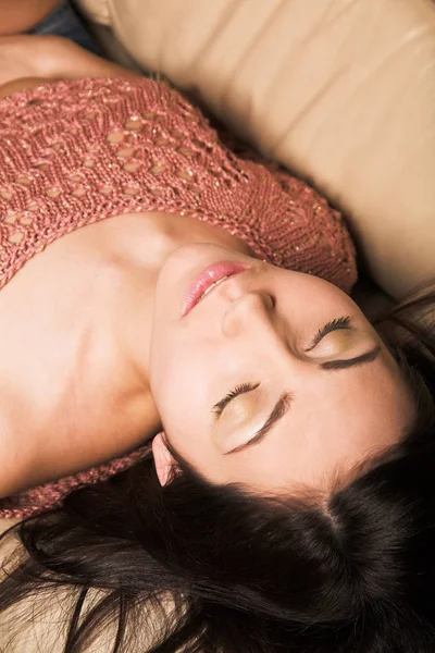 Güzel bir kadın beyaz bir kanepede dinleniyor.