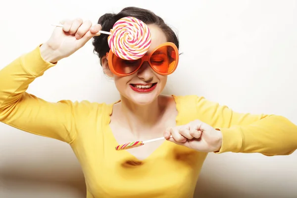 Mulher engraçada usando grandes óculos laranja segurando grande pirulito. Bir. — Fotografia de Stock