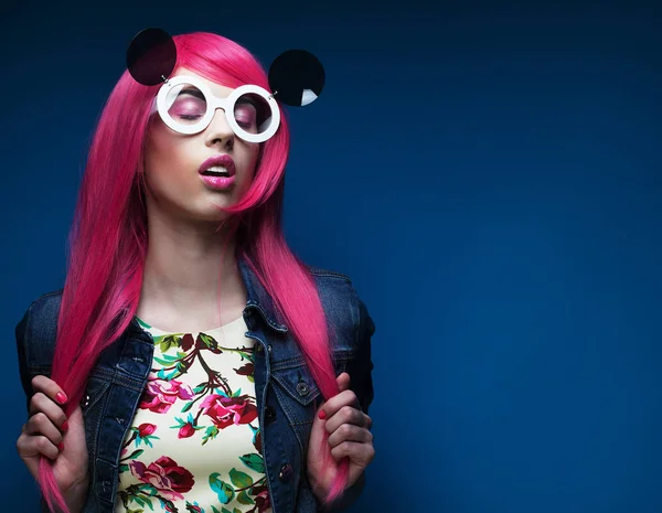 Fashion girl with pink hair and big sunglasses over blue  background — Stock Photo, Image