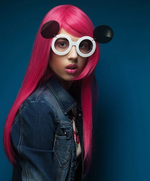 Fashion girl with pink hair and big sunglasses over blue  background — Stock Photo, Image